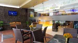 A hotel lobby with wicker furniture, a TV, and a glass partition with 'iCheck Inn' signage. - iCheck inn Nana by Aspira (Bangkok)