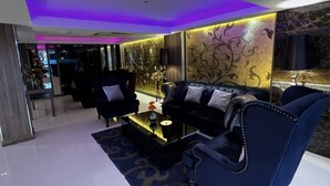 A modern living room with a black leather sofa, a glass coffee table, and a decorative wall panel. - iCheck inn Nana by Aspira (Bangkok)