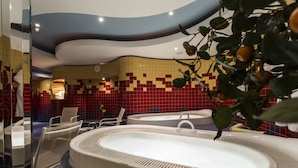 A modern bathroom with two large oval sinks, a mirror, and a chair. - all inclusive Hotel Lohmann (Soelden)