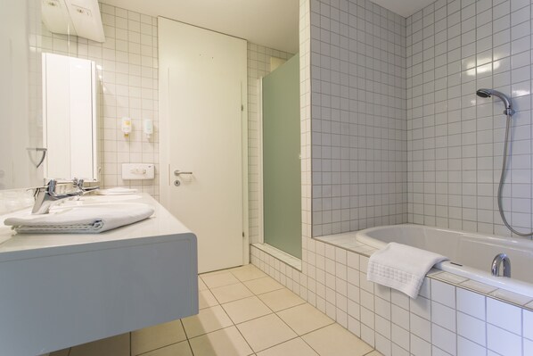 Un baño con lavamanos blanco, espejo, ducha y bañera.
