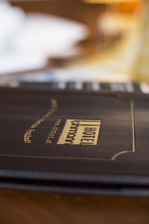 A close-up of a black leather-bound book with the word "HOTEL" visible on the cover.