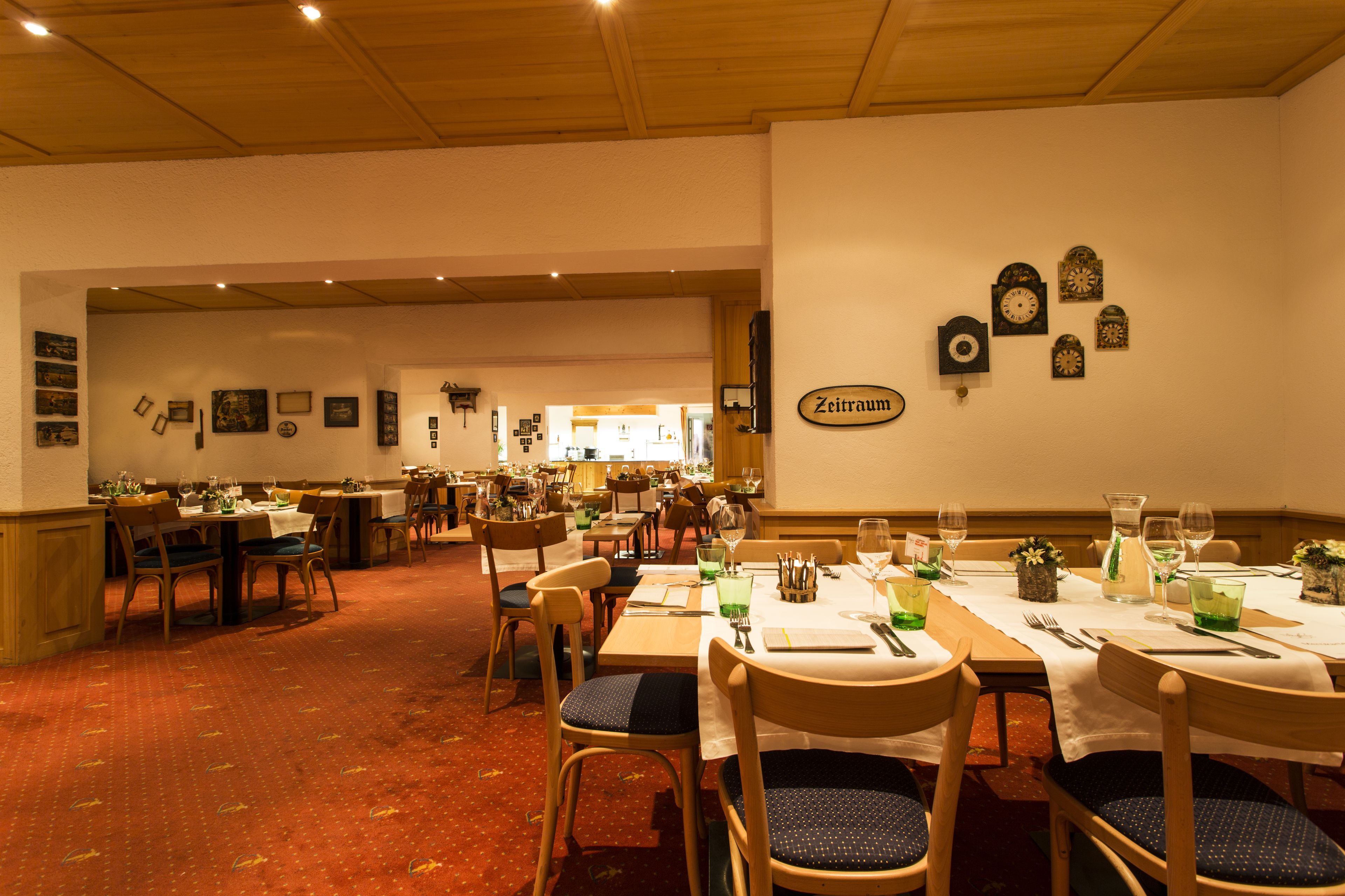 Un restaurante con varias mesas y sillas, un reloj en la pared y cuadros en las paredes.