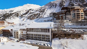 Un hôtel moderne à plusieurs étages, doté de grandes fenêtres et offrant une vue sur une station de ski.