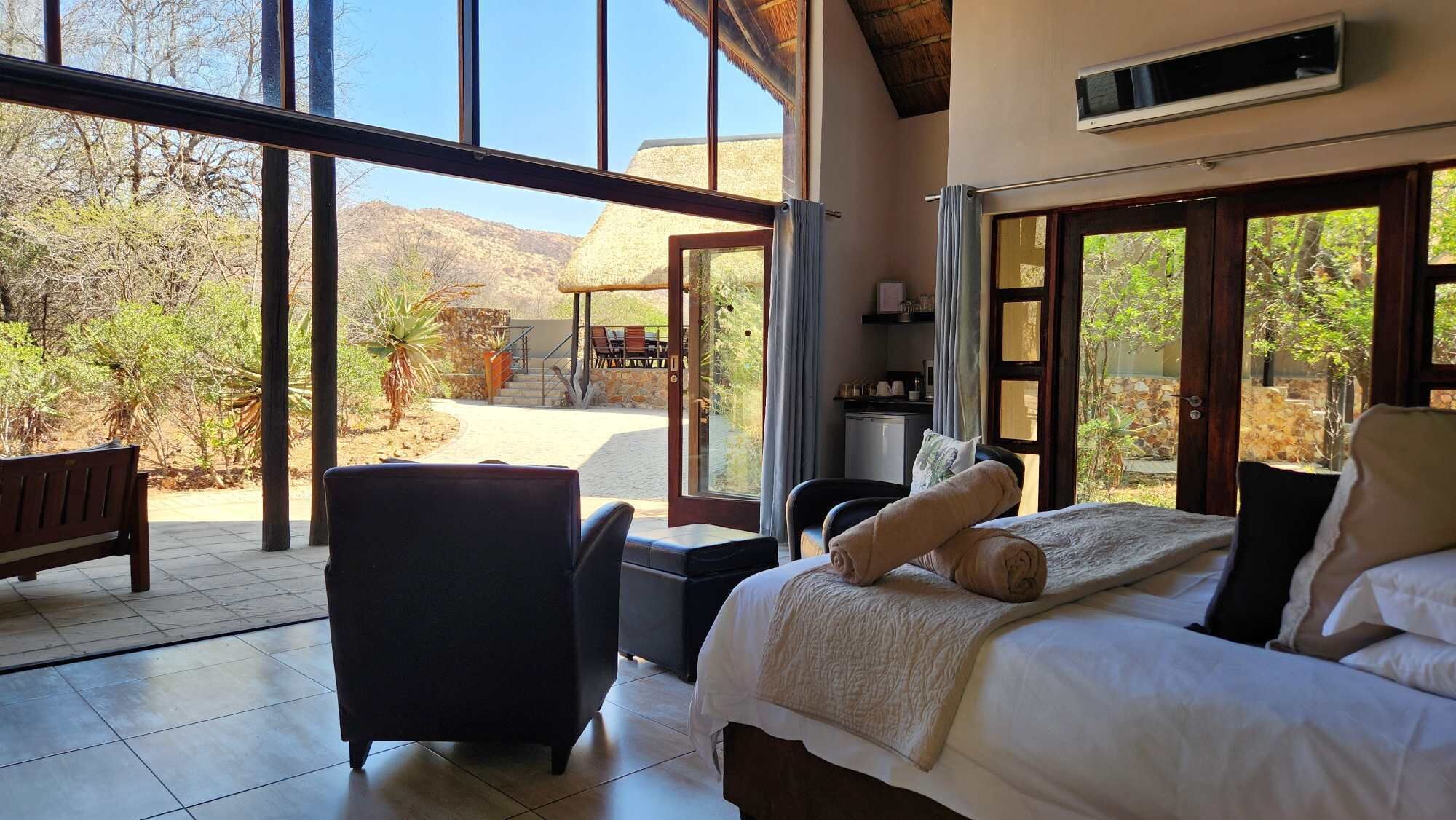 A bedroom with a bed, a chair, and a view of the outdoors.