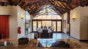 A dining area with a high ceiling, a large window, and a view of the outdoors.