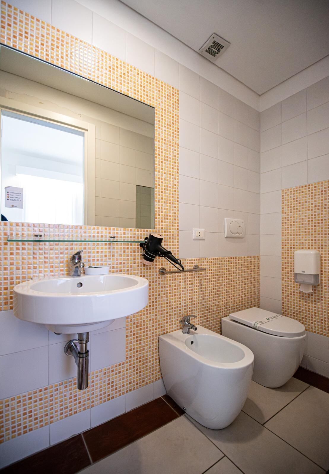 A bathroom with a sink, bidet, toilet, and a mirror.