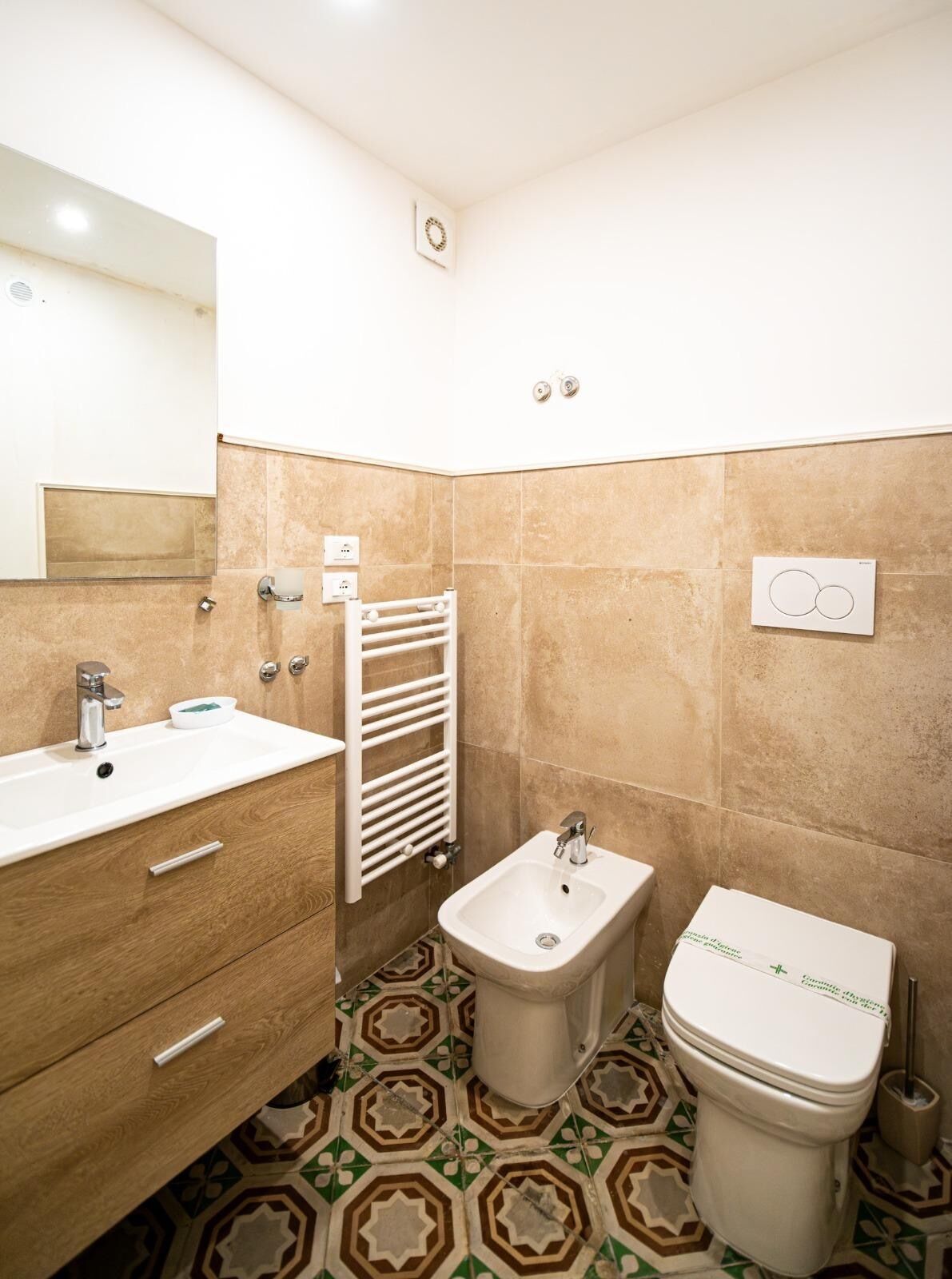 Un baño con lavamanos, bidé, inodoro y perchero para toallas.