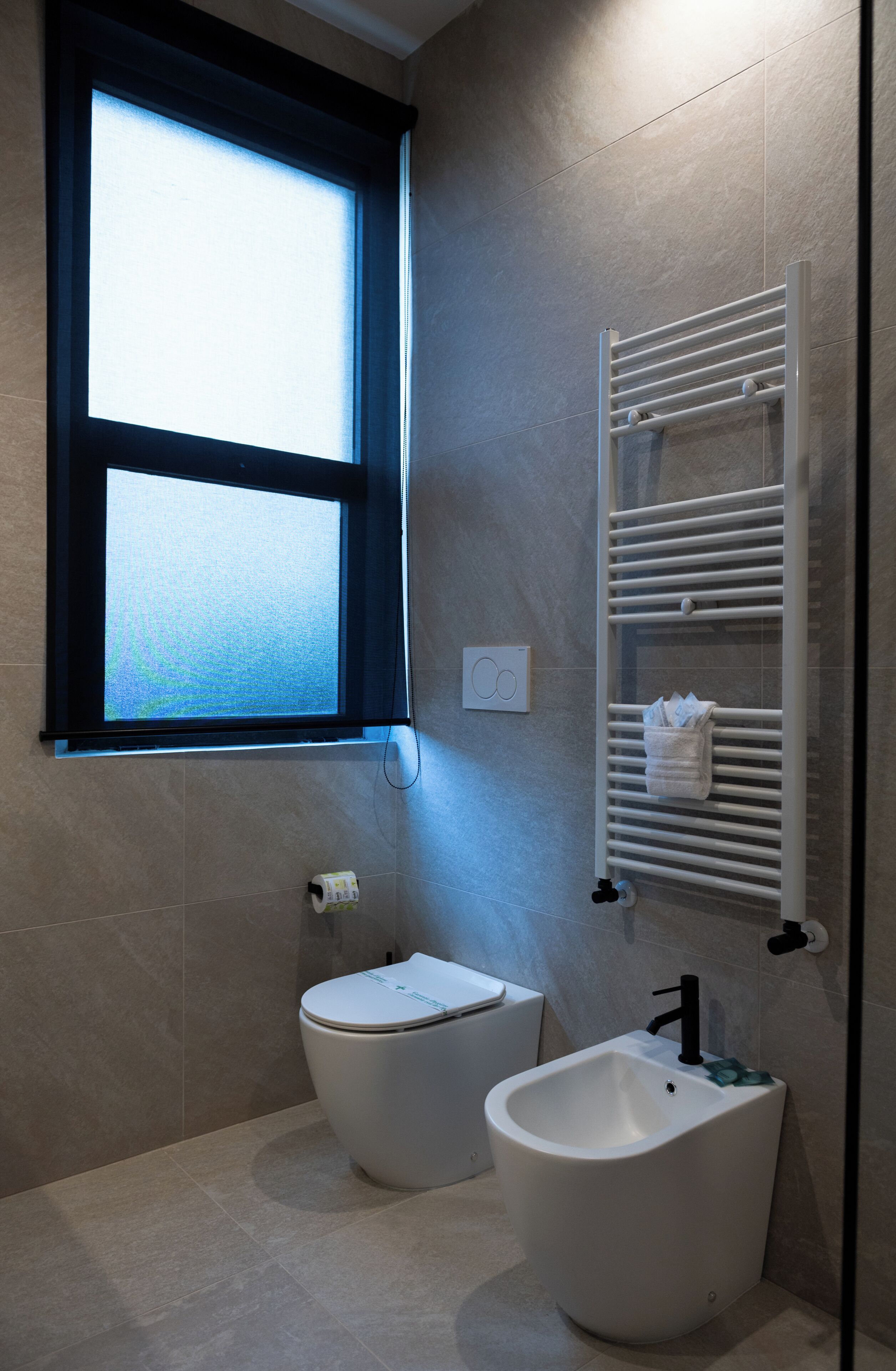 A modern bathroom with a bidet, toilet, and a towel rack.