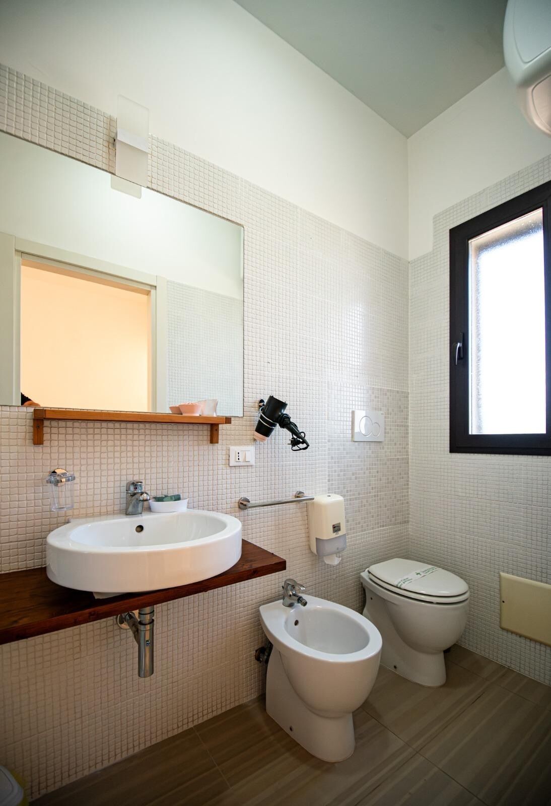 Un baño con lavamanos, bidé, inodoro y espejo.