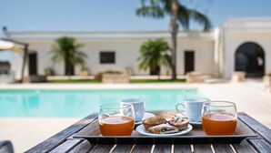A poolside table with a tray of food and drinks, a white cup, and a glass of tea. - Tenuta San Nicola (Novoli)