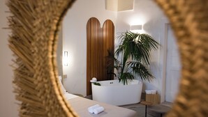 A bathroom with a bathtub, a potted plant, a towel, and a mirror framed by a decorative border. - Tenuta San Nicola (Novoli)