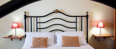 A bed with white linens, two bedside lamps, and two pillows with text.