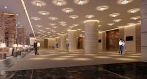A spacious lobby with a high ceiling, multiple columns, and a patterned carpet.