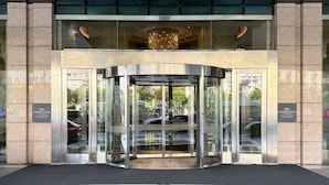 Entrada de un edificio moderno con puerta giratoria, puertas de vidrio y un cartel que indica 'Crowne Plaza'.