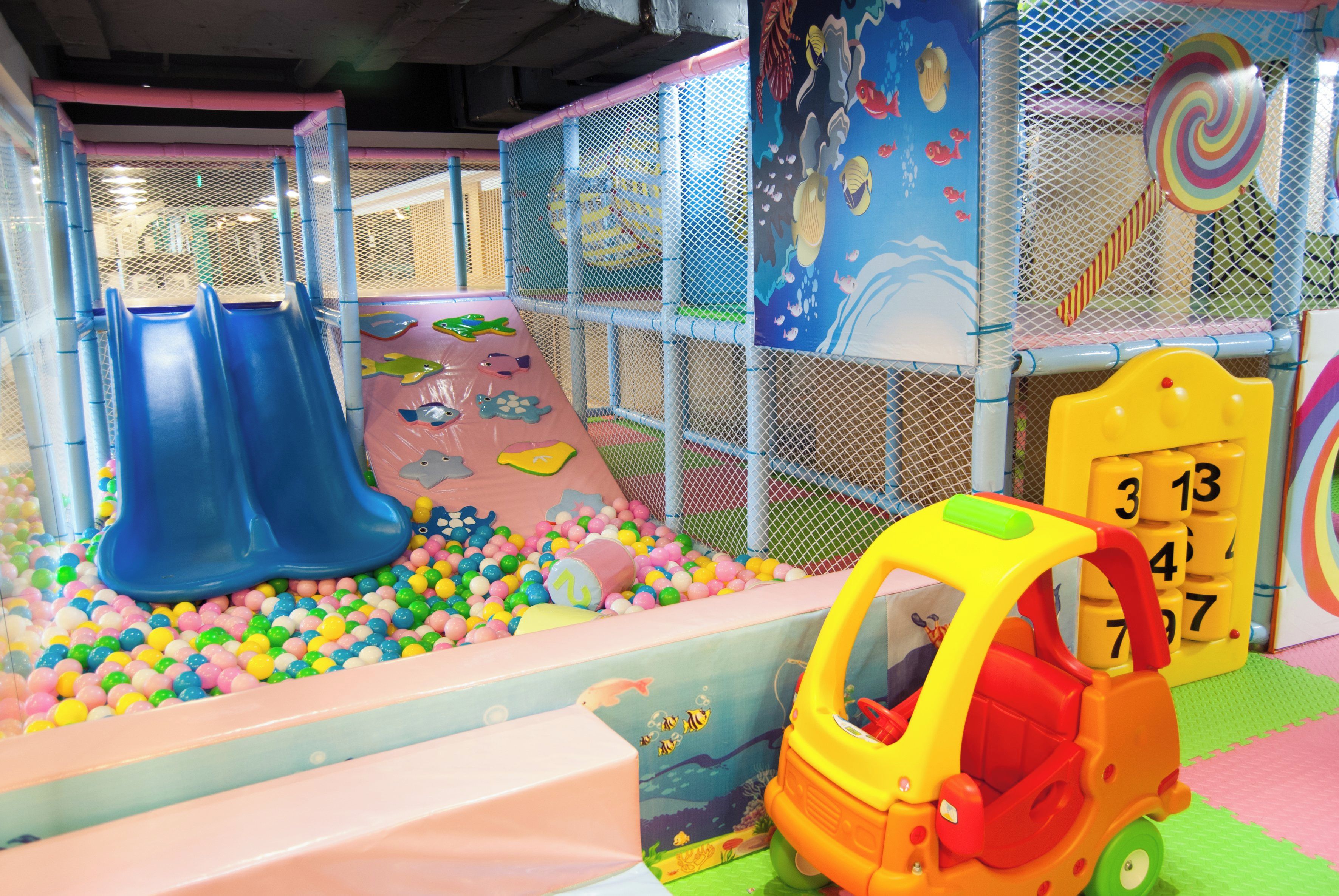 Un área de juegos infantiles con toboganes, una piscina de pelotas y un coche de juguete.