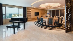 Una sala moderna con un piano, una mesa de comedor redonda y una araña.