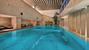 Una piscina interior con sillas de descanso y un techo de listones de madera.