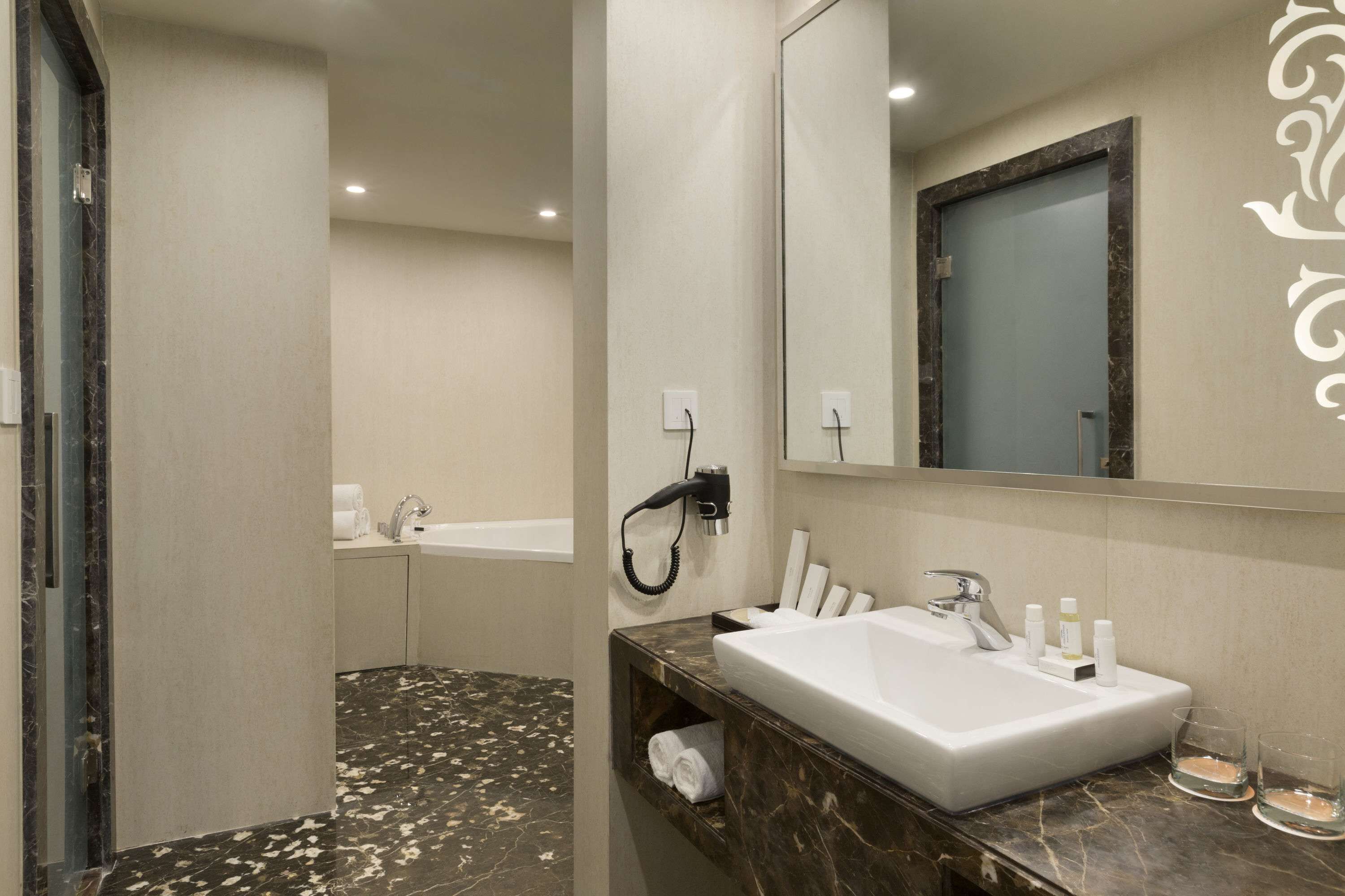 A modern bathroom with a marble vanity, a large mirror, a bathtub, and a shower.