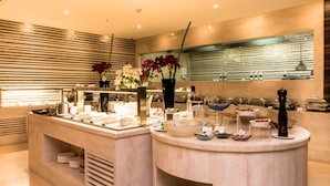Uma bancada de café da manhã moderna com diversas opções de comida e um vaso de flores.