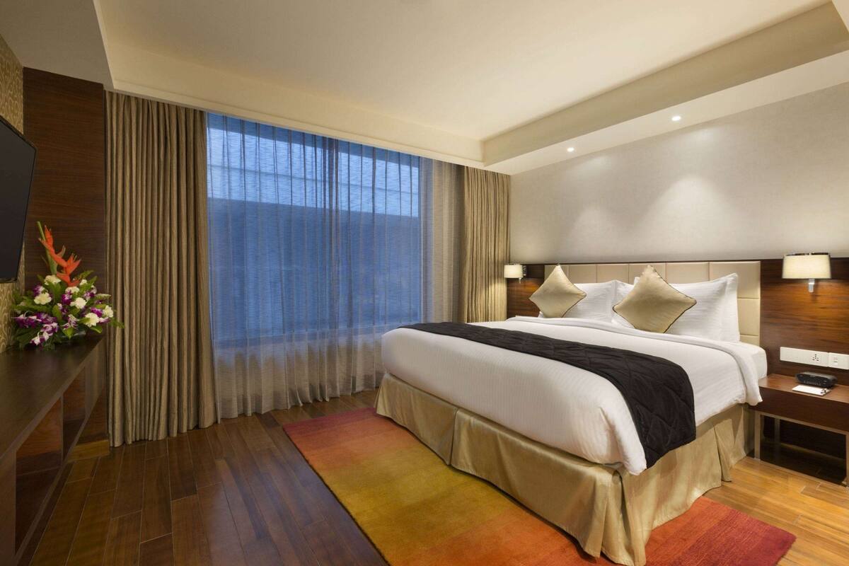 Une chambre d’hôtel moderne avec un grand lit, un bureau et une télévision.