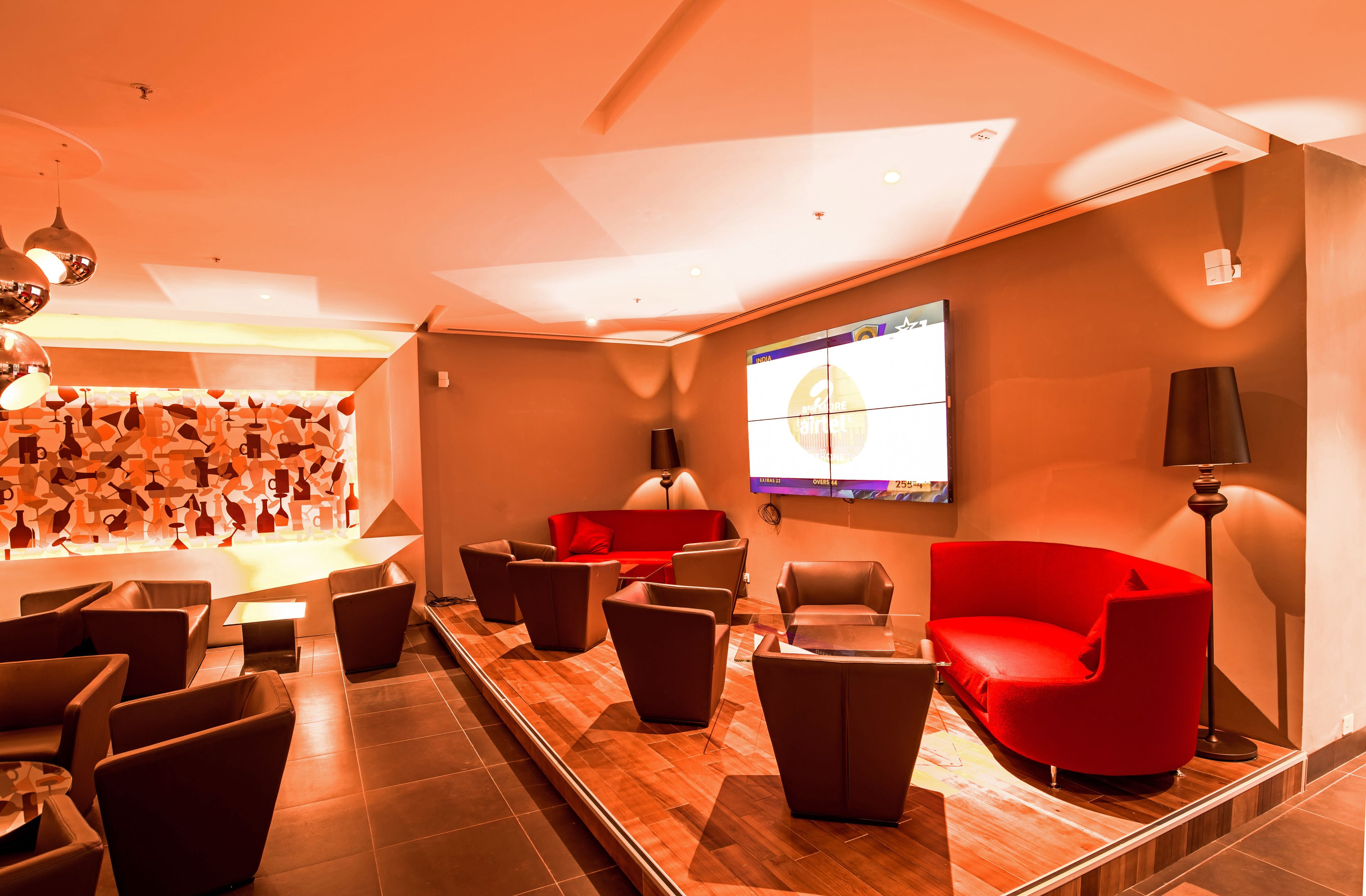 Un espace de détente moderne avec des canapés en cuir, un téléviseur à écran plat et un mur décoré de motifs.