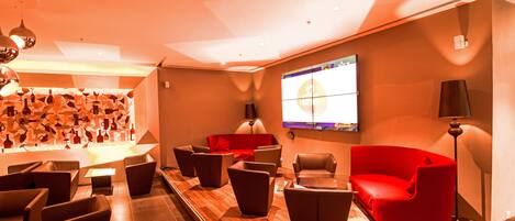 A modern lounge area with leather sofas, a flat-screen TV, and a patterned wall.