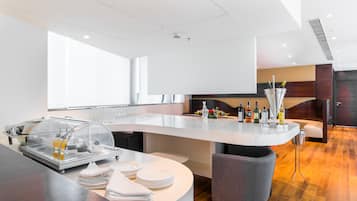 Una cocina moderna con una isla curva, un compartimento de vidrio para alimentos y una zona de estar con un banco acolchado.