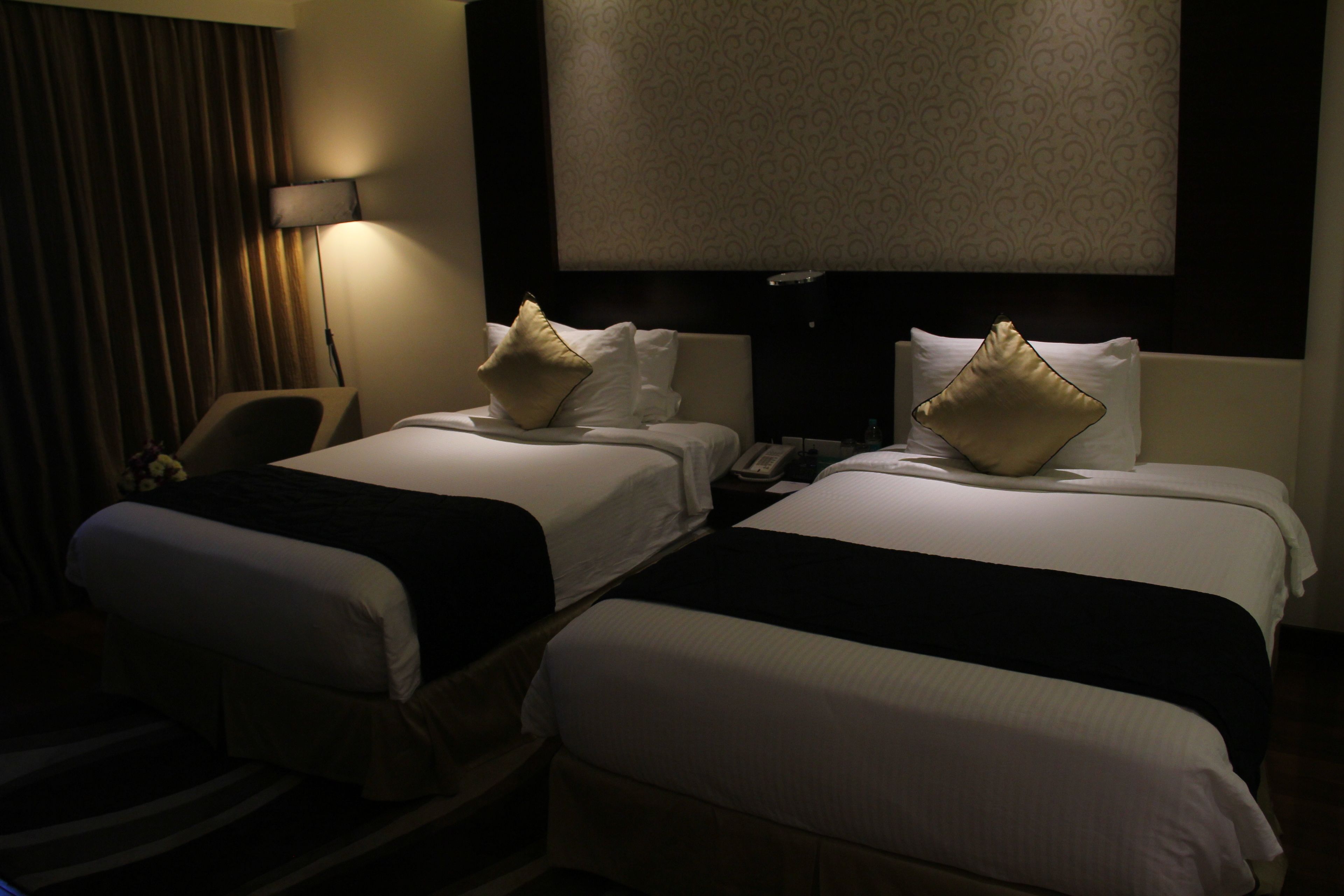 Una habitación de hotel con dos camas, un escritorio, una silla y una lámpara.