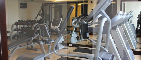 A gym with treadmills, dumbbells, and weight machines.