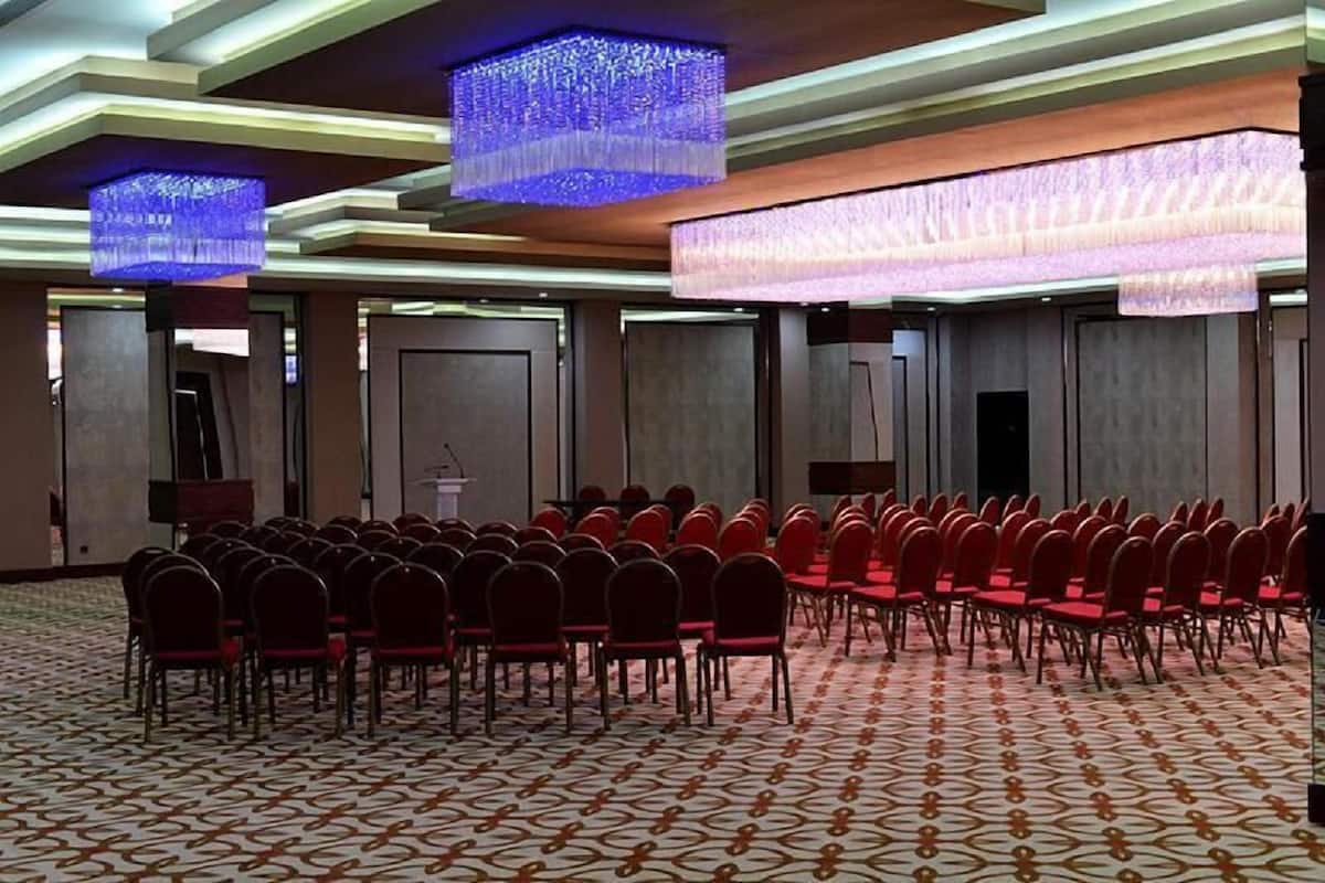 A conference room with rows of chairs, a podium, and a patterned carpet.