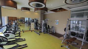 A gym with exercise equipment, mirrors, and a yellow floor.