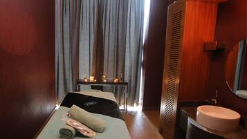 Relax in a serene space with a massage table, vanity, and candles.