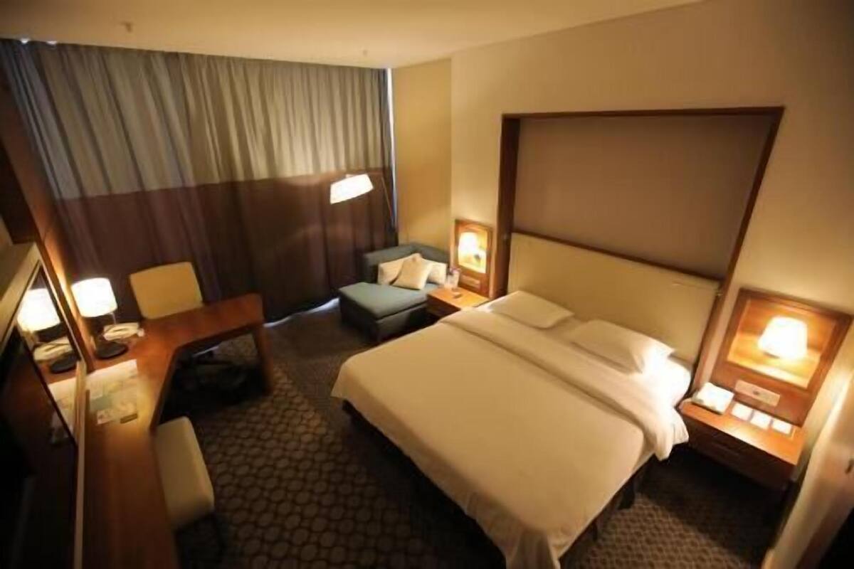 Une chambre d’hôtel avec un grand lit, un bureau, une chaise, un canapé et deux lampes de chevet.