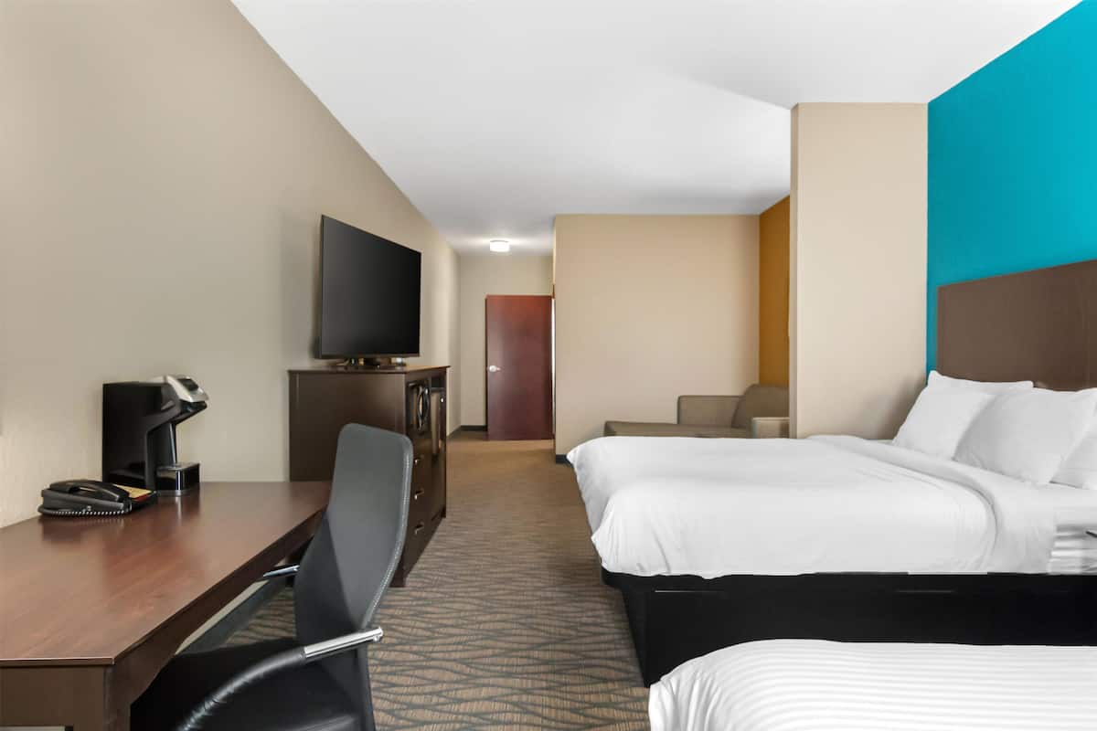 A hotel room with a bed, a desk with a chair, a television, and a coffee maker.