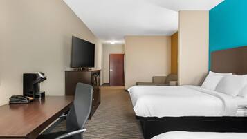 Een hotelkamer met een bed, een bureau met stoel, een televisie en een koffiezetapparaat.