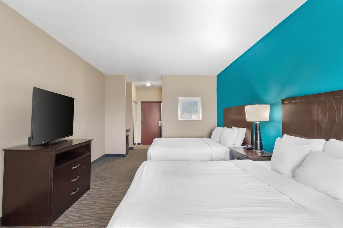 A hotel room with two beds, a TV on a dresser, a lamp, and a painting on the wall.