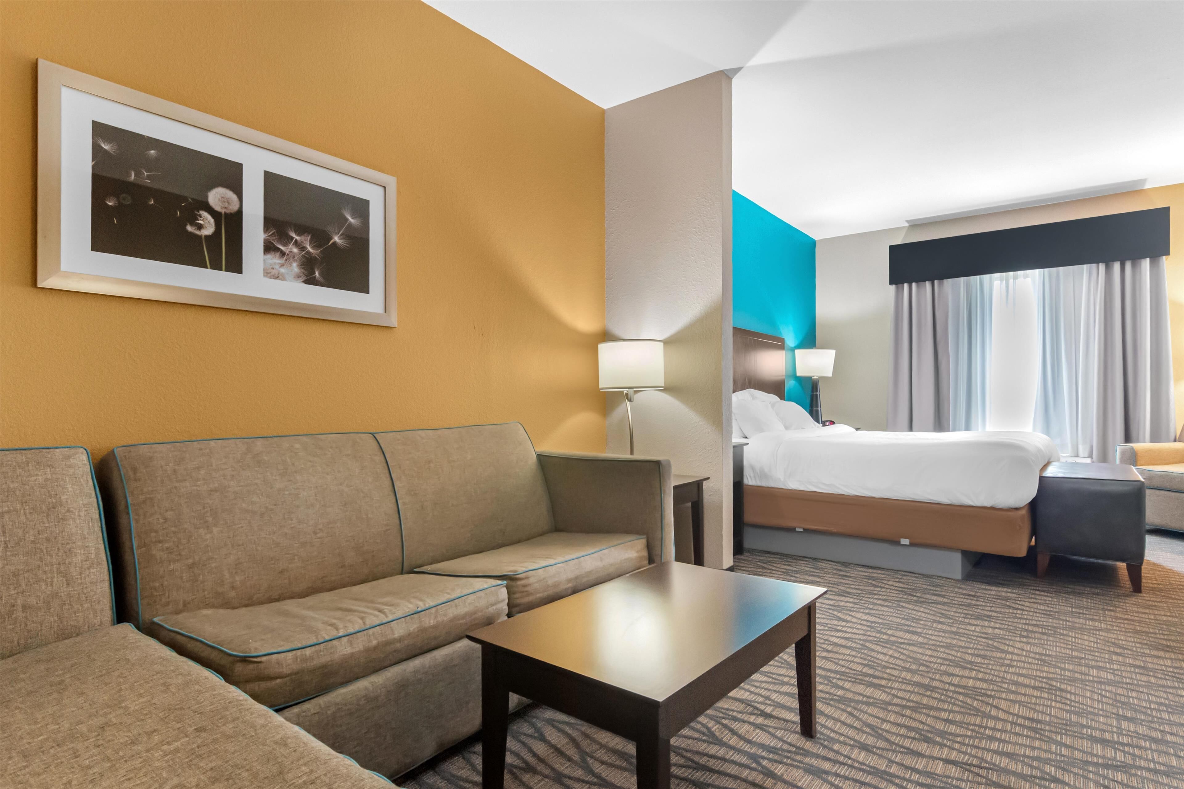 A hotel room with a sofa, a small table, a bed, and a nightstand.