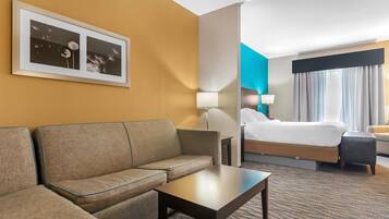 A hotel room with a sofa, a small table, a bed, and a nightstand.