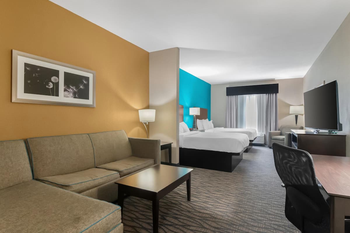 A hotel room with a sofa, a bed, a desk, and a television.