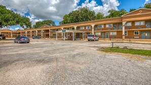 A motel with multiple rooms, a covered parking area, and a clear sky. - Budget Inn and Suites (Crowley)