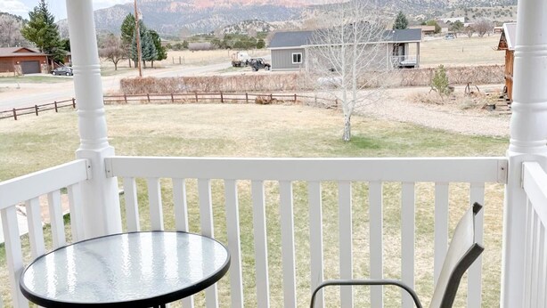 A covered patio with a table and two chairs, overlooking a rural landscape with mountains and sparse vegetation. - Bryce Canyon Livery Bed & Breakfast (Tropic)