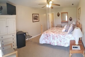 A bedroom with a bed, a desk, a chair, a wardrobe, a ceiling fan, and a television. - Bryce Canyon Livery Bed & Breakfast (Tropic)