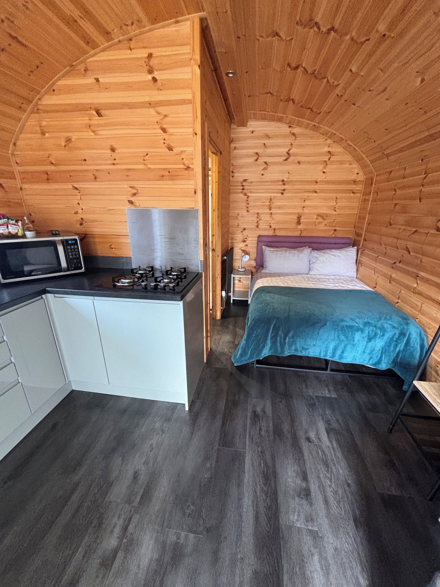 Une pièce compacte comprenant un coin cuisine, un lit et une petite table de chevet.