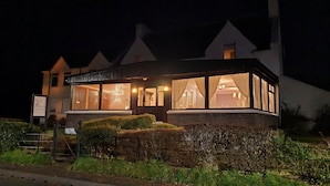 A guest house with large windows, a signboard, and a well-maintained hedge. - Atholl House Skye (Dunvegan)