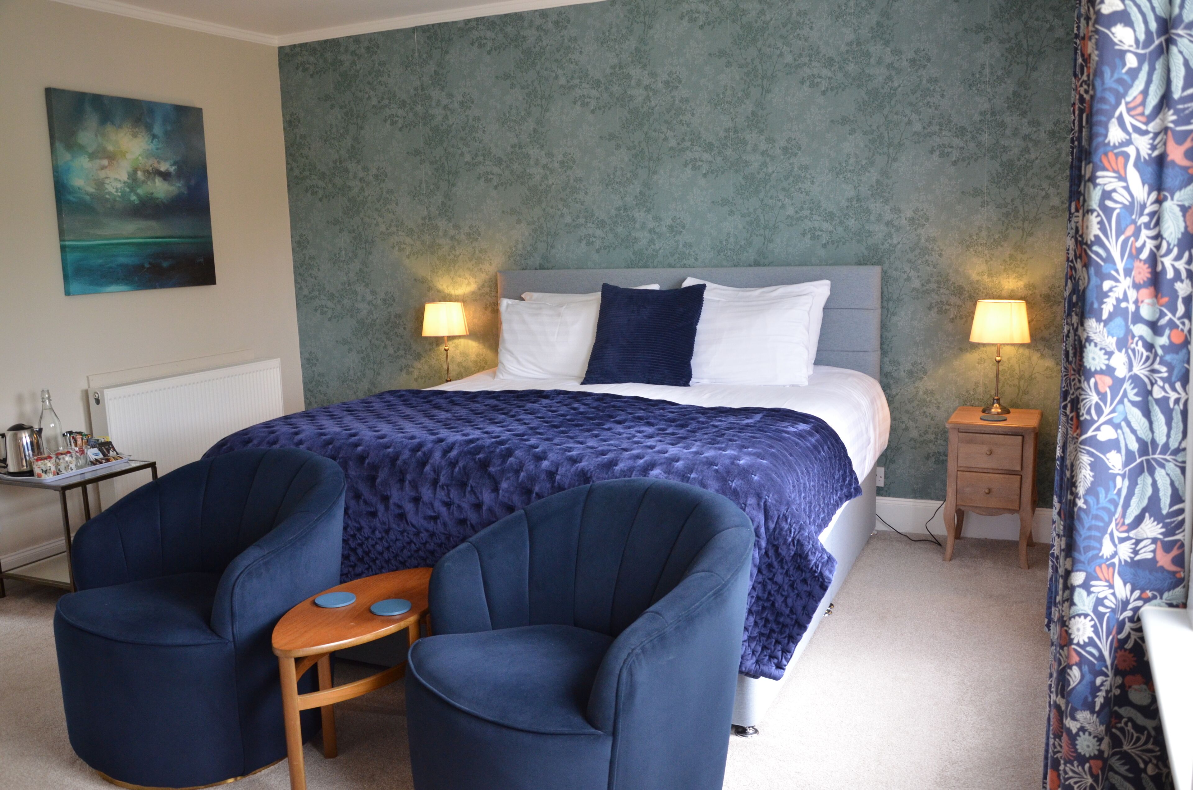 A bedroom with a bed, two bedside lamps, a nightstand, a chair, and a small table.