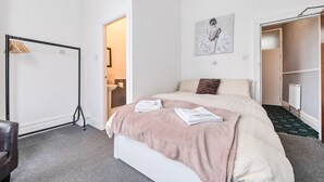 Una camera da letto con un letto, un armadio, un termosifone e una porta che dà su un'altra stanza.