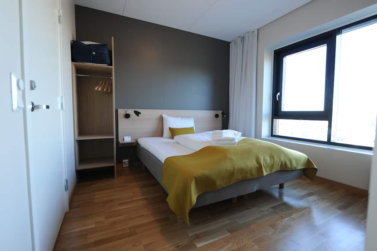 A bedroom with a bed, a wardrobe, and a window.