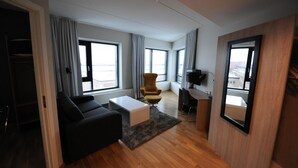 A modern living room with a black sofa, a yellow armchair, a white coffee table, and a large window. - Tananger Apartment Hotel  (Sola)