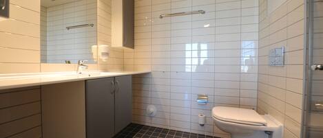 Un baño moderno con lavamanos, espejo y inodoro blancos.