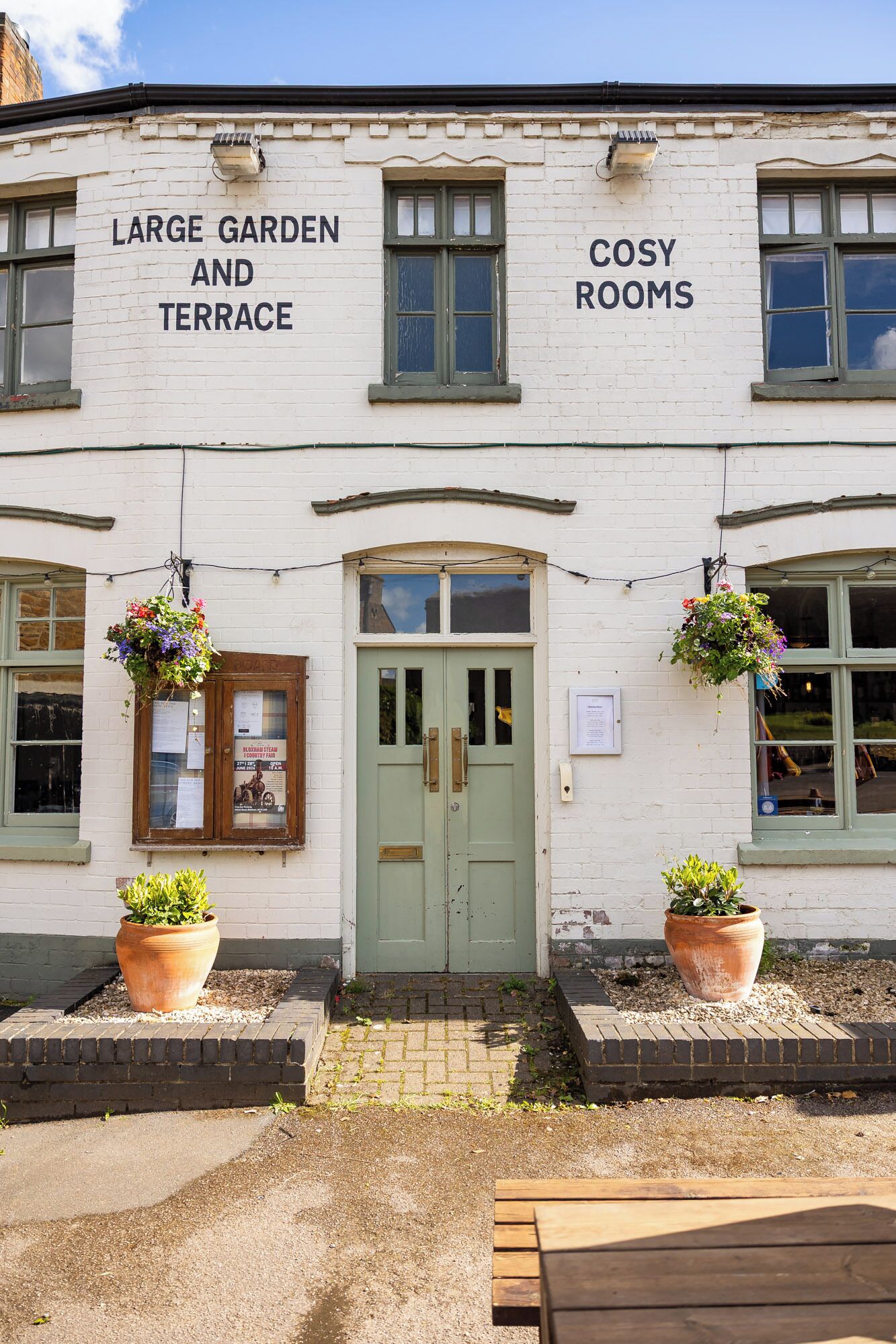 A building with a sign reading 'Large Garden and Terrace' and 'Cosy Rooms'.